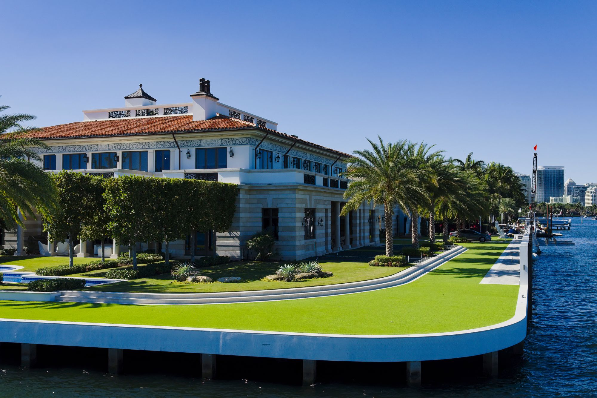 White limestone Palm Beach estate with arched loggia framed by royal palms