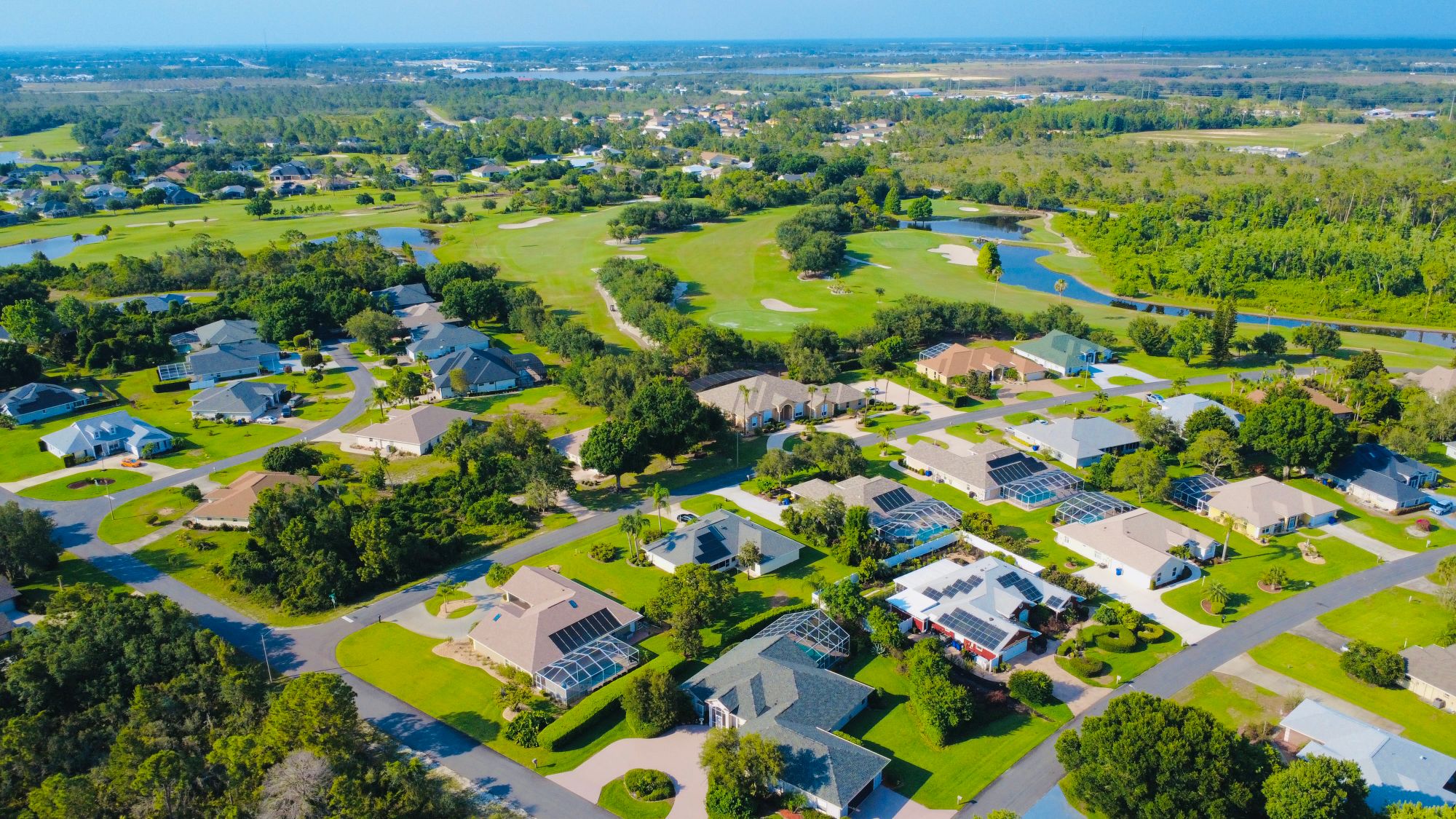Tree-lined Palm Beach Gardens street beside a manicured golf fairway at morning light